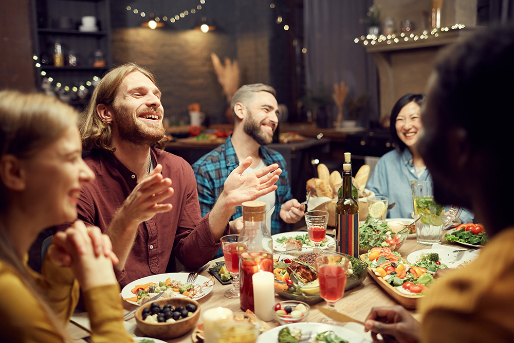 Group of young people laughing and enjoying each other's company during dinner.